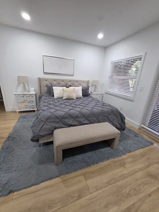 Primary bedroom with a tufted headboard and gray bedding, cleaned by AYA Nova