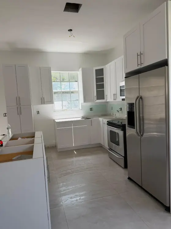 Newly installed kitchen with white cabinets and new tile floors